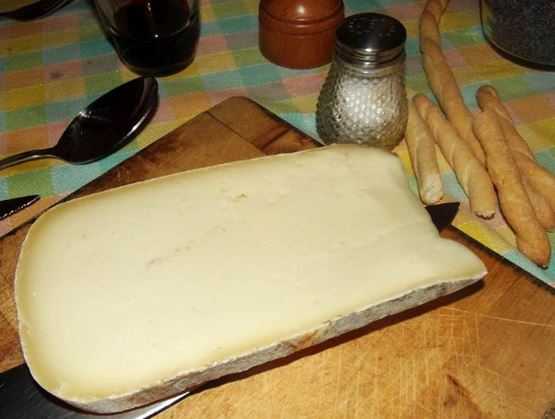 Ivory-colored Raschera cheese block on a cutting board.