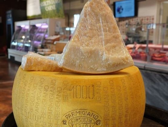 Wheel of Parmigiano Reggiano with wrapped wedges in the foreground.