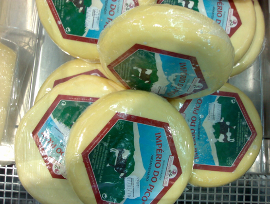 Fromages portugais Império do Pico empilés, à croûte jaune et étiquette verte représentant une vache devant le mont Pico aux Açores.