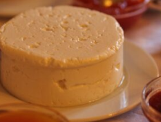 Fromage frais portugais de Rabaçal présenté sur une assiette blanche, entouré de petits bols de confiture ou condiments.