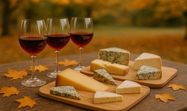 Plateau de fromages affinés accompagné de verres de Beaujolais nouveau sur une table automnale élégante.