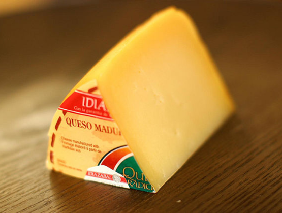 morceau d'Idiazàbal posé sur une table marron 