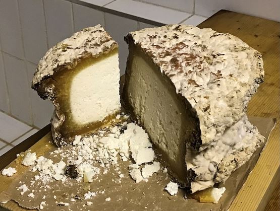 Morceau émietté du fromage gris du Tyrol sur une table en bois
