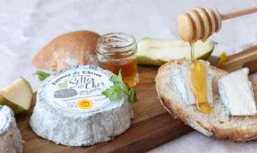 Fromage de chèvre Selles-sur-Cher AOP accompagné de miel et de poire, servi sur une tranche de pain artisanal.  une mise en scène gourmande évoquant la douceur et l’authenticité du terroir.