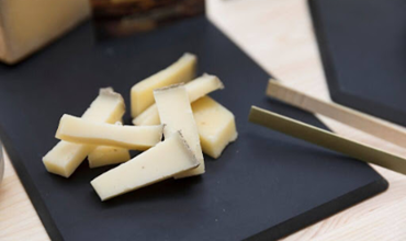 Morceaux de fromages posés les uns sur les autres avec un pince métalisée posée 