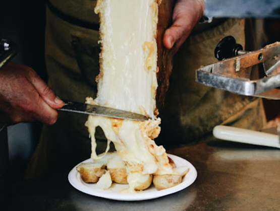 une fondue épaisse allant se posée sur des pommes de terres présentées dans une assiette blanche